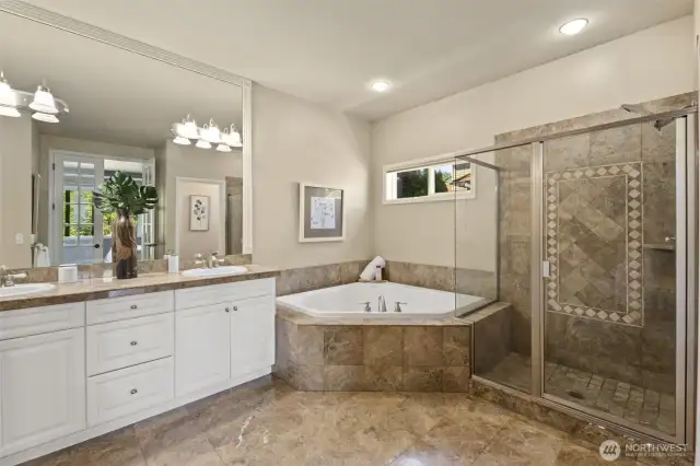 Primary bathroom with marble flooring, marble countertops and marble surrounding the bath.