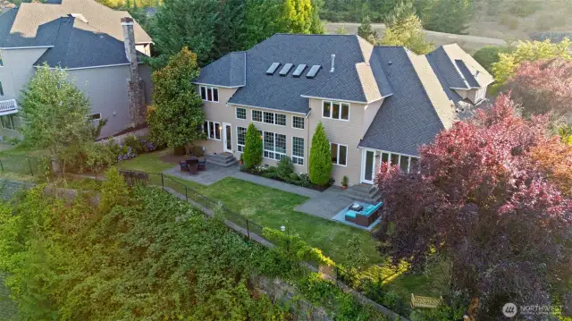 Drone view showcasing the home's expansive windows, dual patios, and serene natural surroundings with no homes behind.
