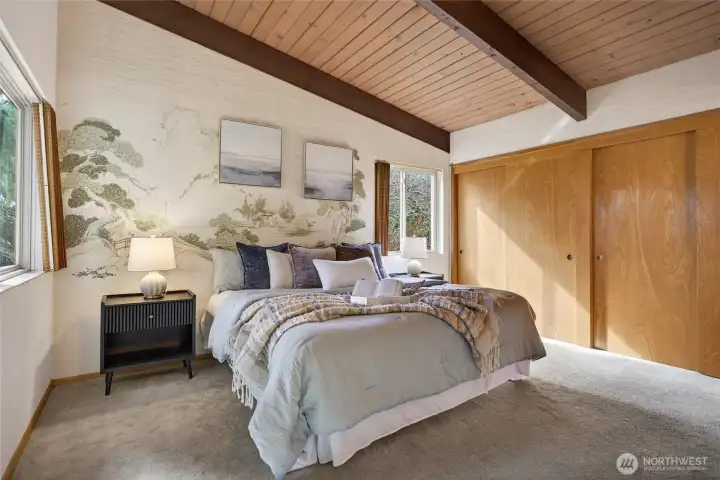Primary bedroom with a vaulted ceiling and an accent wall of chinoiserie wallpaper.