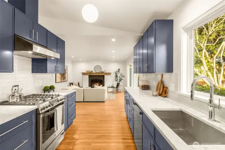 The stunning kitchen is a showpiece with custom blue-gray cabinetry, honed Carrera marble counters, premium stainless appliances, with gas cooking. Spacious deep sink and undermount lighting.