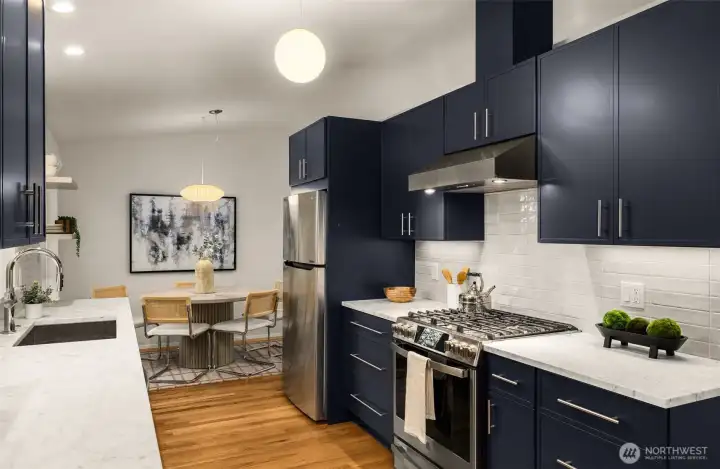 The stunning kitchen is a showpiece with custom blue-gray cabinetry, honed Carrera marble counters, premium stainless appliances, with gas cooking. Spacious deep sink and undermount lighting.