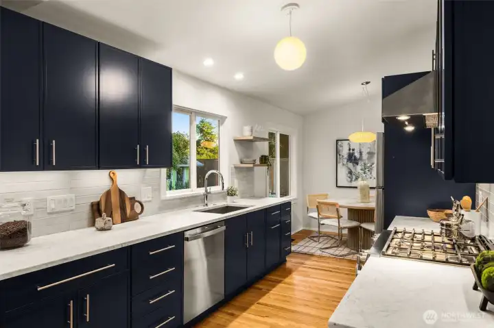The stunning kitchen is a showpiece with custom blue-gray cabinetry, honed Carrera marble counters, premium stainless appliances, with gas cooking. Spacious deep sink and undermount lighting.
