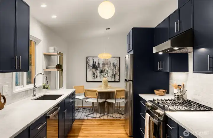 The stunning kitchen is a showpiece with custom blue-gray cabinetry, honed Carrera marble counters, premium stainless appliances, with gas cooking. Spacious deep sink and undermount lighting.