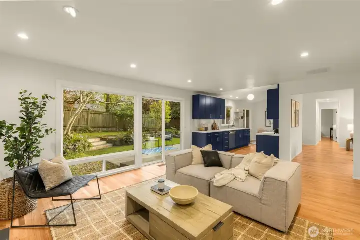 Family room flows effortlessly into the kitchen and backyard. The inviting family room features a wood-burning fireplace, dramatic floor-to-ceiling windows, and seamless patio access for indoor-outdoor living.
