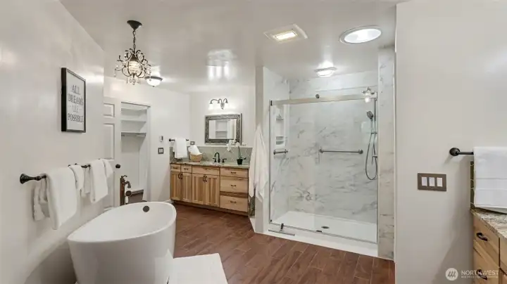 Spa-like bath with heated floors, separate sinks, and granite countertops.