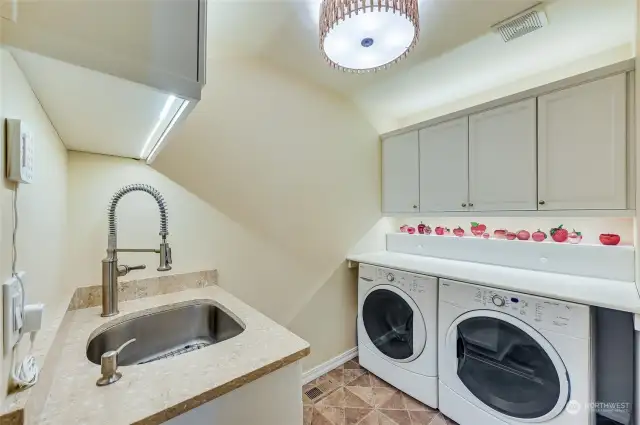The laundry room has loads of added cabinets, a handing clothes folding counter, sink, and faucet. Uplights and under cabinets lights plus a custom overhead light!