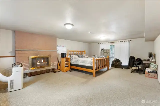 Large bonus room downstairs with wood burning fireplace and sliding glass door that opens to covered patio.