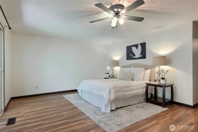 Primary bedroom with new laminate flooring. Sliding glass doors lead to a private deck.