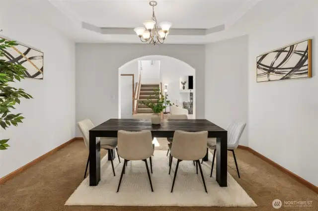 Dedicated dining area with tray ceiling surrounded by arch entryways