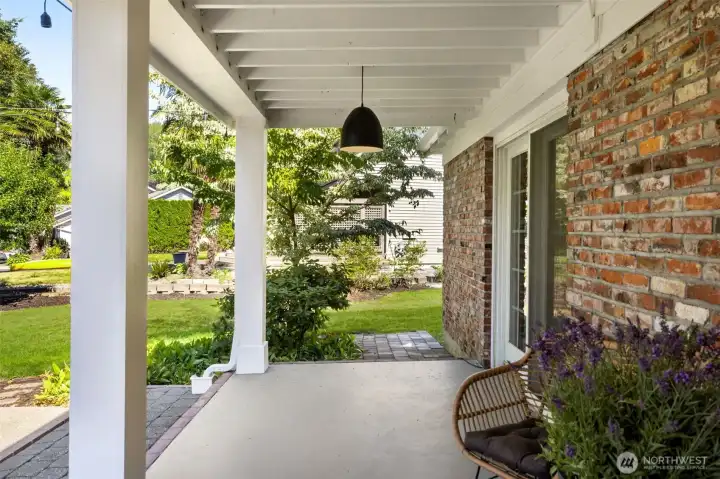 Covered patio space blends indoor comfort with outdoor living, perfect for morning coffee surrounded by greenery.