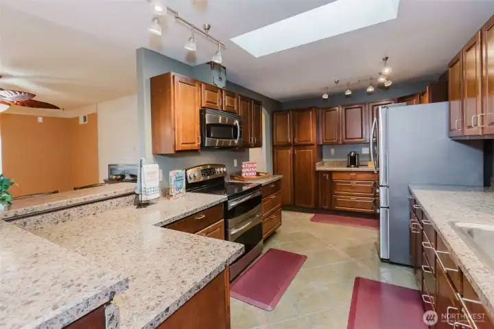 Bright kitchen with skylight, stainless steel appliances, and functional layout.