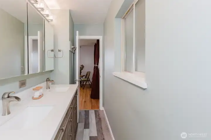 Updated half bath featuring double sinks, modern fixtures, and vinyl plank flooring.