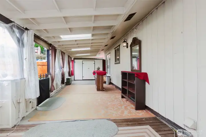 Expansive covered outdoor living space with privacy curtains and multiple skylights.