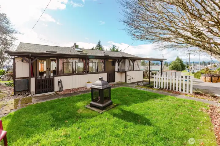 Backyard with lawn area, covered patio, and Olympic Mountain views.