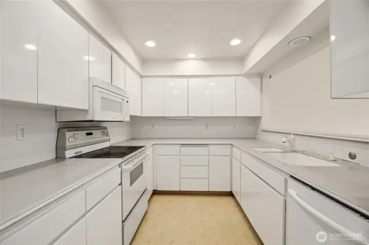 Spacious with a multitude of cabinet and counter space  Corian counters / tile backsplash / linoleum floor  Bright white cabinets with adjustable shelves & pull out lazy susan  Fridge, electric stove, dishwasher, and built-in microwave