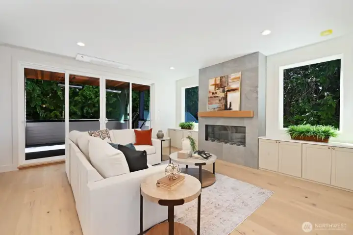 The open living room features an electric linear fireplace bordered by base cabinets with quartz tops. Great room for entertaining with double slider access to covered deck.