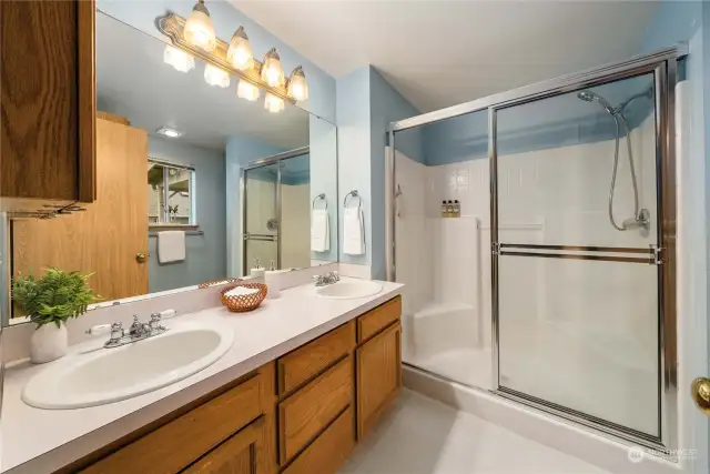 Primary bath with double sinks, lots of storage, and fiberglass shower surround.