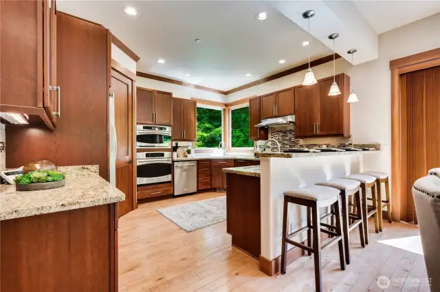 Beautiful custom kitchen features soft-close cherry stained cabinets with pullouts shelves.