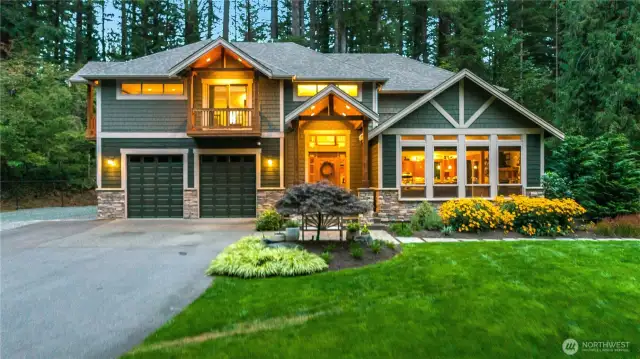 This home is nestled on a sunny flat yard surrounded by a lush forest.
