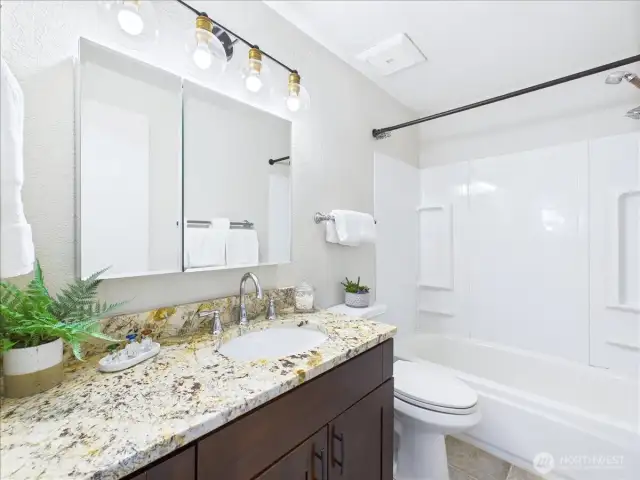 Granite countertop and dark cabinets in the primary bathroom.