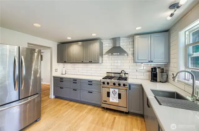 Amazing Kitchen with slab counters, stainless steel appliances including Viking range, undermount sink, painted cabinets, and hardwood floors.