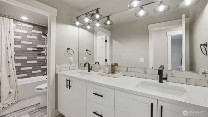 Guest bathroom with double sinks and private shower/tub and toilet.