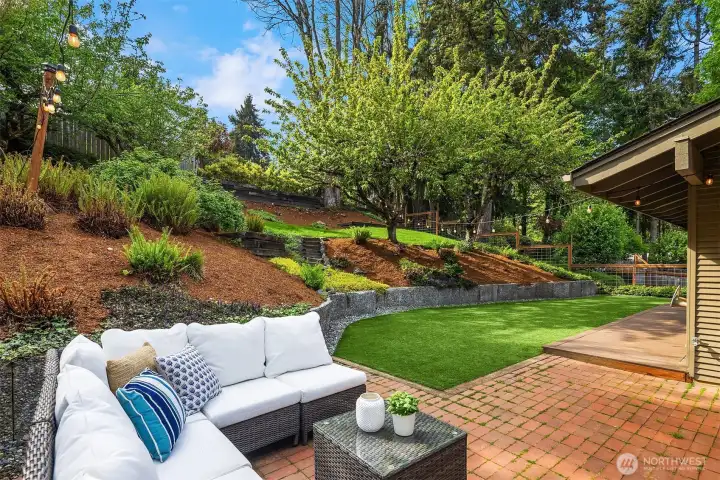 The fully fenced terraced backyard offers a tranquil private retreat with turf and natural lawns, lovely mature landscaping, and garden beds for flowers and vegetables.