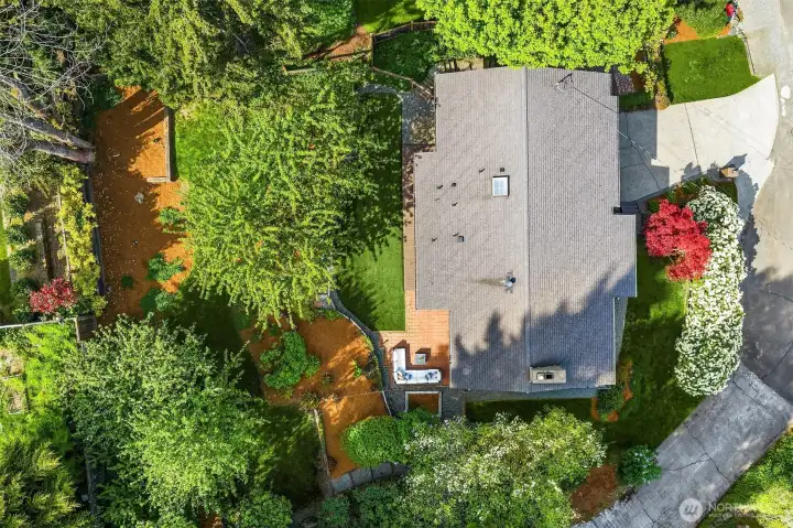 Aerial view of property offering a fully fenced backyard, brick patio, turf and natural lawns, and beautiful mature landscaping.