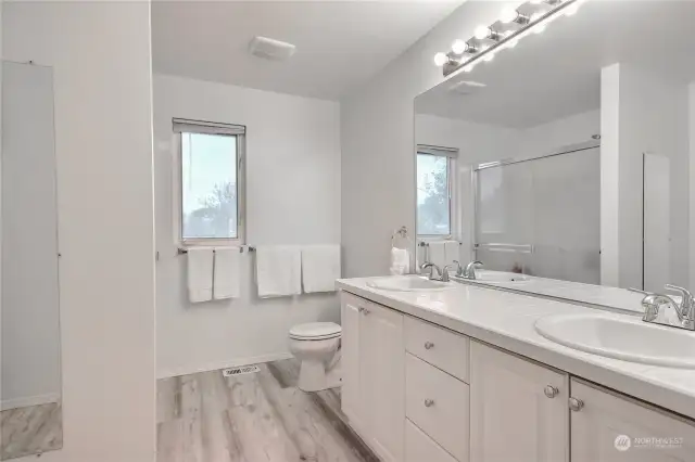 Primary bathroom has a dual sink vanity, large shower, brand new LVP flooring & a big walk-in closet