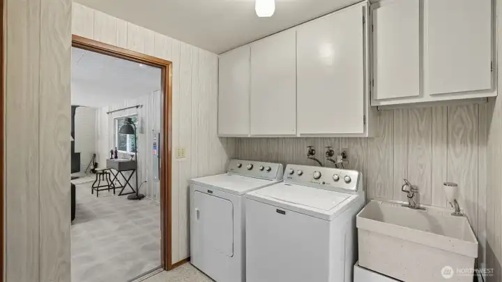 Bright laundry area with plenty of cabinetry and convenient utility sink.