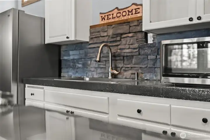 Kitchen detail featuring stone backsplash, stainless appliances, and rustic touches.