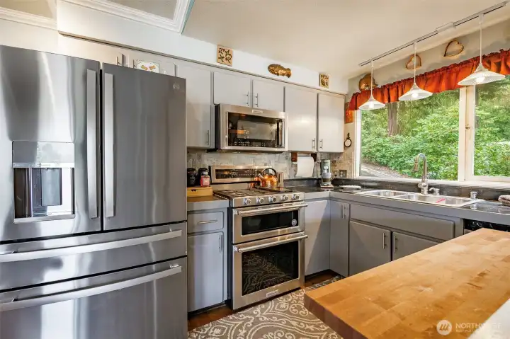 Stainless steel appliances lend a sleek, modern touch, while the rustic butcher block countertop adds warmth and character—offering both style and additional prep space.