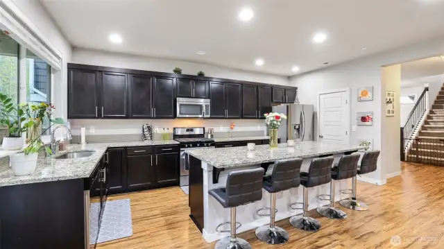 Enjoy granite slab countertops, sleek stainless steel appliances, a gas range, a dream-sized island with an extended eating bar, and a spacious pantry for all your storage needs.