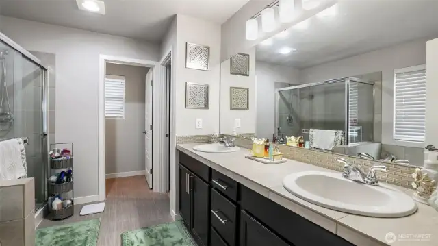 Primary bath with a dual sink vanity, separate shower, and soaking tub. Off the primary bath is a walk-in closet.