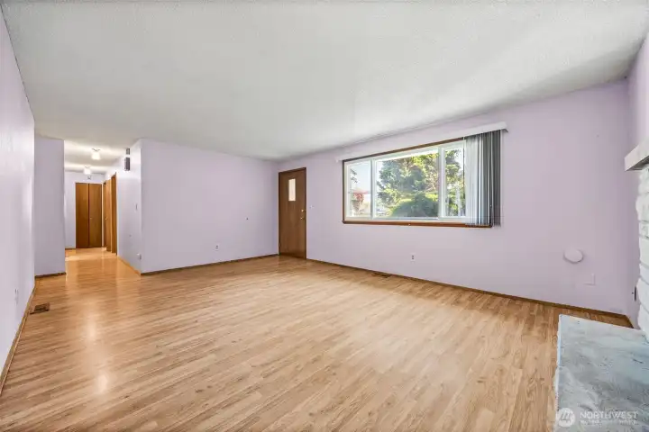Spacious living room just off the entry, featuring a cozy wood burning fireplace and plenty of natural light - perfect for relaxing or entertaining.