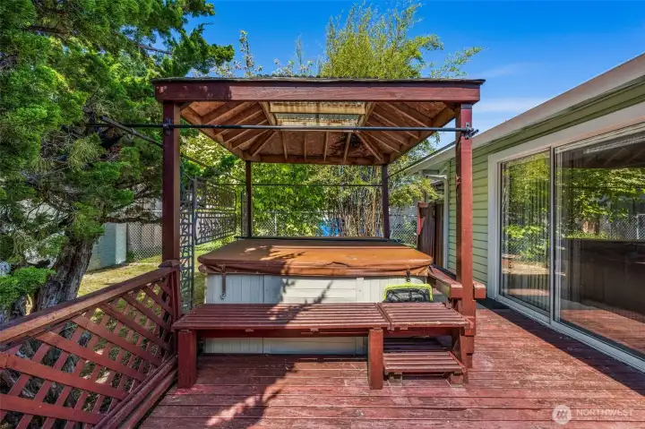 Fully fenced backyard with deck and hot tub — ideal for barbecues, entertaining, gardening, or relaxing in privacy.