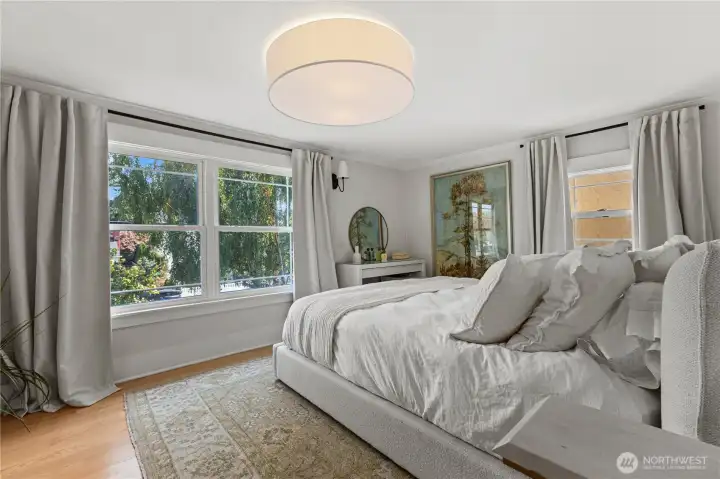 Primary bedroom filled with natural light, offering a serene retreat with views of mature landscaping