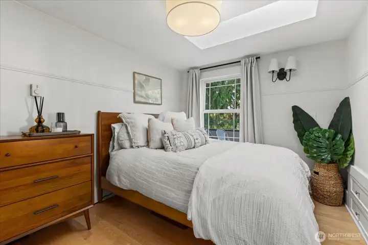 Second bedroom with hardwood flooring, skylight, and built-in storage