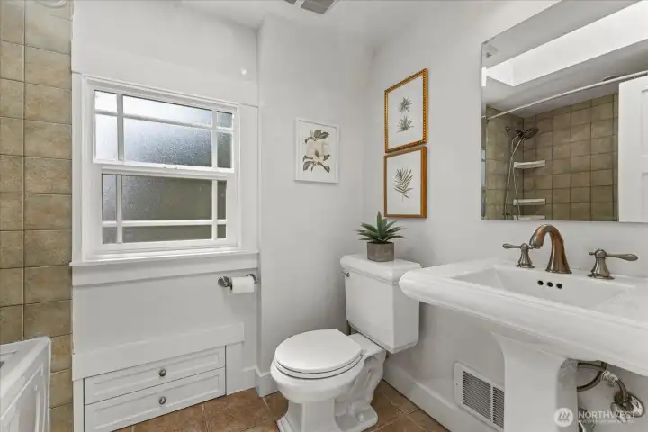 Charming upstairs bathroom with jetted tub/shower, pedestal sink, and built-in storage