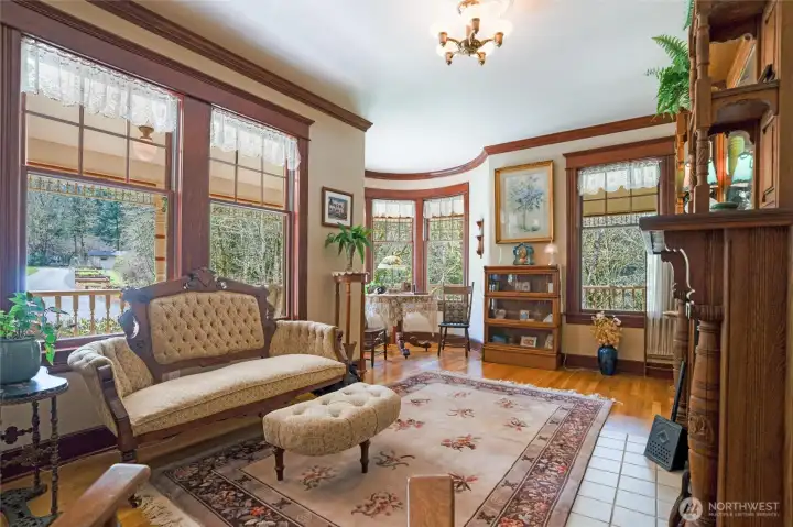 An elegant parlor with wood-burning fireplace and hardwood flooring is a treat as you step inside to this period appropriate space.