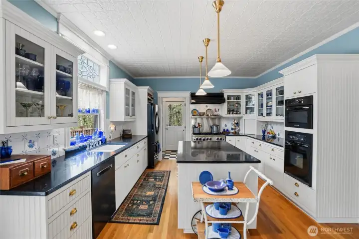 Authentic tin celiing decorates this amazing kitchen, with its gorgeous corian counters, Blue Star 6-burner gas cooktop (brand new door), additional wall oven, and custom white cabinetry.  Notice the beautiful leaded glass window above the no-edge sink.