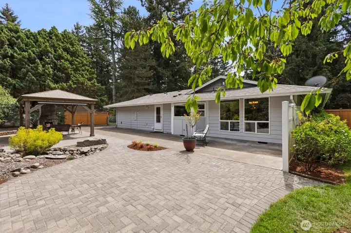 Paved backyard patio creates your own private outdoor oasis with a sprinkler system installed for the flower beds.