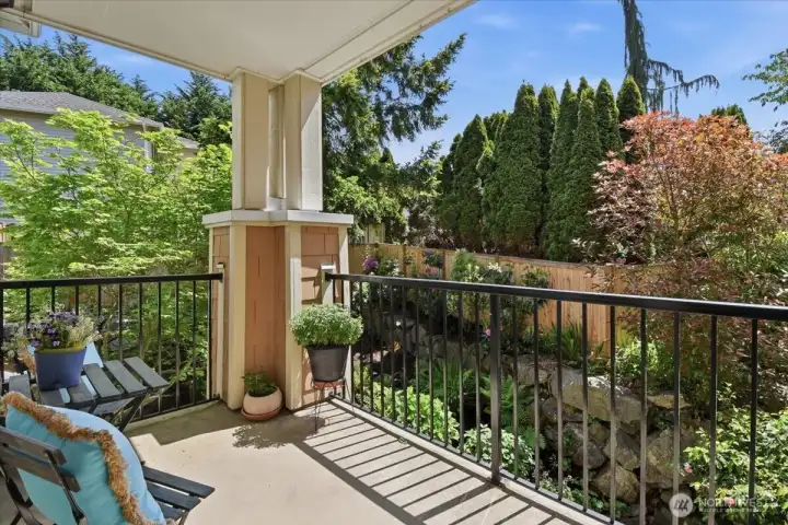 A private balcony area that overlooks green space and a flowered area