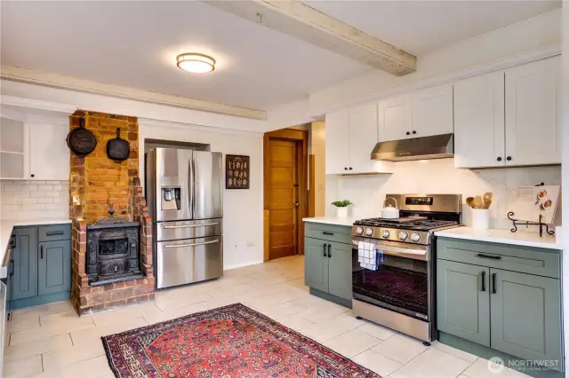 The original stove stands in contrast to the modern gas range. The door to the right of the fridge opens to a large storage room with backyard access and the bathroom is just a few feet down the hall.