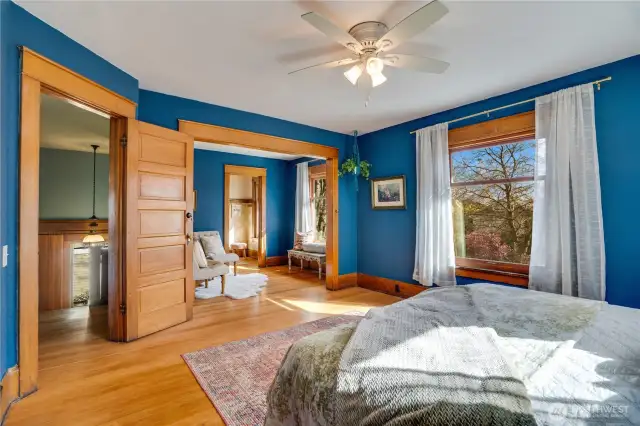 A cased opening leads to the sitting room where another east-facing window captures the morning light. Beyond the sitting room a walk-in closet with its own window waits.