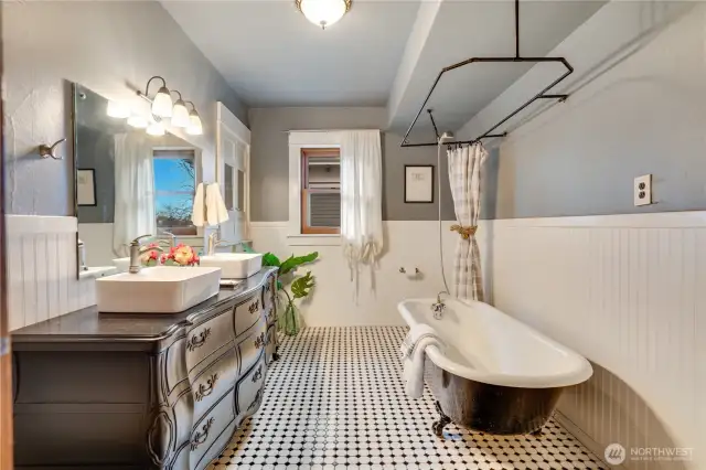 Just down the hall find the full bath with its original linen cupboard for storage. Simple white wainscoting, the claw foot tub, laundry chute, and tiled floor preserve early 20th century character.