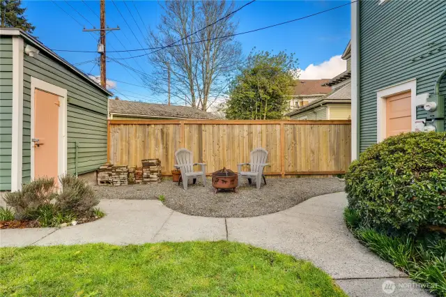 The single-car, detached garage has its own sub-panel and an automatic door. Paved pathways connect the garage to the door into the back storage room, the kitchen steps, and the back gate that opens to the alley.