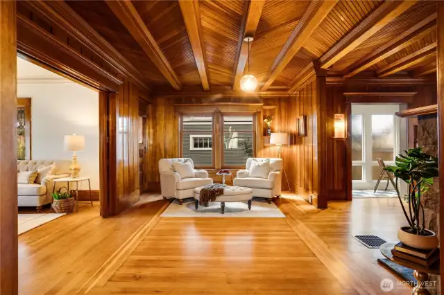 Beamed, herringbone ceilings, floor to ceiling paneling, and distinctive fir floors wrap the living room in the beauty of all its original millwork. Notice this first glimpse into the little conservatory off the den.