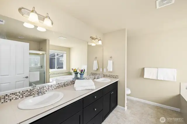 Double sinks tiled countertop in primary bathroom.