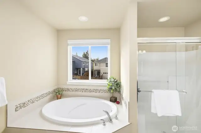 Deep soaking tub and long shower stall in primary bathroom.